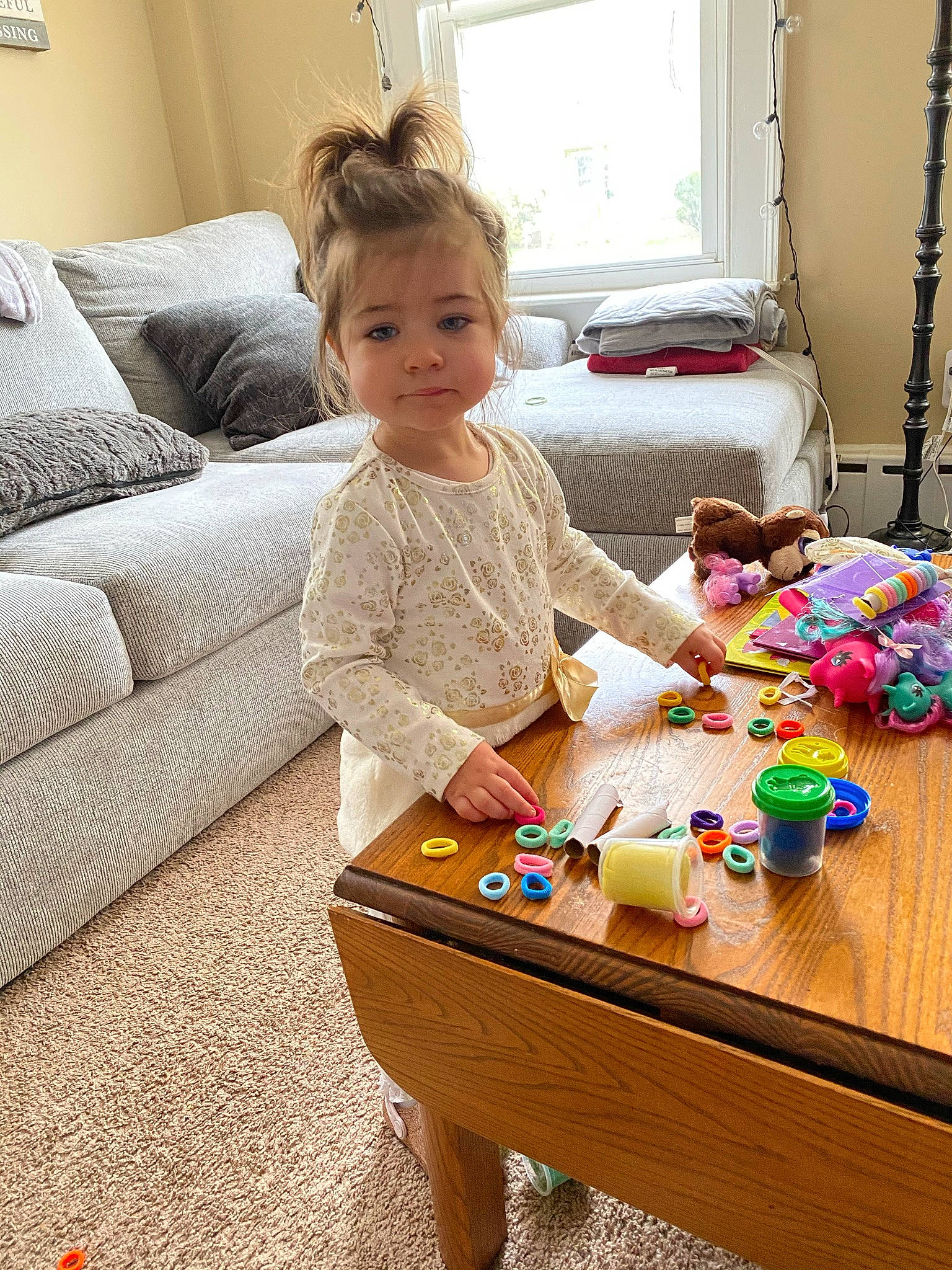 Lilliana is registered to the contest to win money with this photo: baby, baby_playing_with_toys, baby_toddler_clothing, child, comfort, couch, curtain, flooring, furniture, living_room, person, picture_frame, room, sharing, smile, table, textile, toddler, toy, window