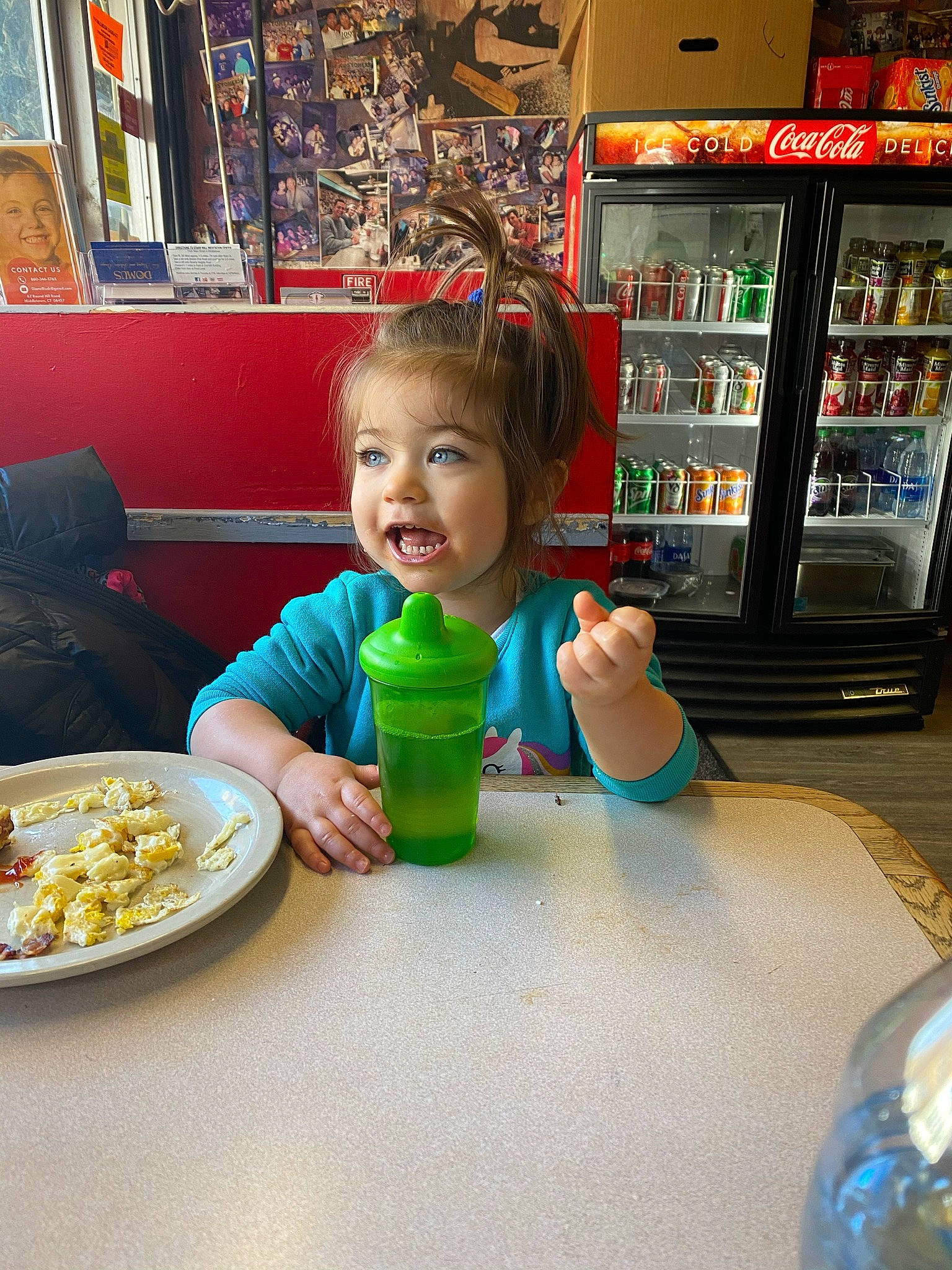 Lilliana joined the competition — help win amazing prizes! blue, bookcase, bottle, chair, child, convenience_store, drink, drinkware, food, fun, joy, person, picture_frame, plastic_bottle, plate, shelf, shelving, sitting, smile, table