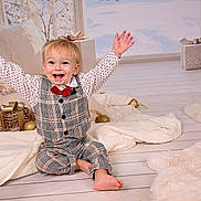 Conrad a rejoint le concours — aidez-le/la à gagner de superbes lots ! toddler, child, smiling, happy, plaid_outfit, red_bow_tie, barefoot, holiday_decor, christmas_tree, wrapped_gifts, golden_ornaments, blankets, cozy, indoor, floor, festive, decorations, cute, joyful, portrait