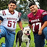 bulldog, dog, football, football_players, sports_jerseys, team_portrait, outdoor, park, grass, family, two_people, smiling, crown, pet, athlete, sports, uniform, portrait, trees, daylight