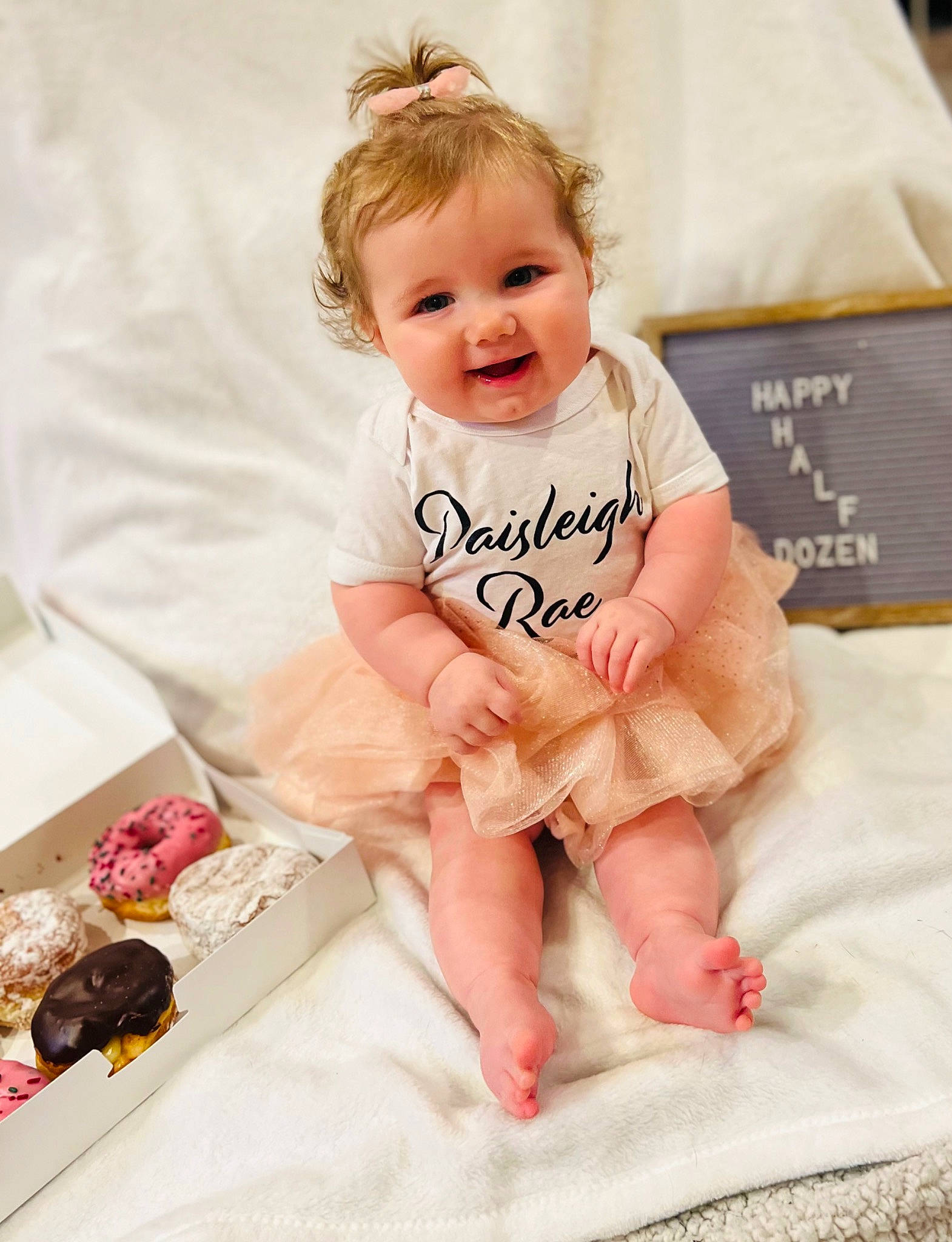 Paisleigh is registered to the contest to win money with this photo: baby, baby_toddler_clothing, cheek, child, comfort, eye, face, foot, fun, happy, head, linens, person, pink, product, sitting, skin, sleeve, smile, textile