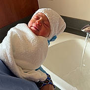 Ailani is registered to the contest to win money with this photo: newborn, baby, towel, hat, glove, hand, sink, water, bathroom, sleeping, infant, person, wrapped, white, blue, skin, face, closeup, rest, comfort