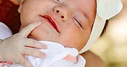 Mylie is registered to the contest to win money with this photo: adorable, arm, baby, child, closeup, cute, expression, face, headband, headwear, infant, outdoor, peaceful, portrait, rest, skin, sleeping, soft_light, white_clothing, young