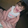 Mylie joined the competition — help win amazing prizes! baby, blanket, child, clothing, cute, expression, face, hair, happy, indoor, joyful, laughing, person, pink, sitting, skin, smiling, tank_top, toddler, young_child