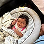 baby, infant, blanket, baby_seat, smile, curly_hair, indoor, cozy, comfort, child, cute, person, clothing, soft_texture, pattern, relaxing, happy, portrait, toddler, hands