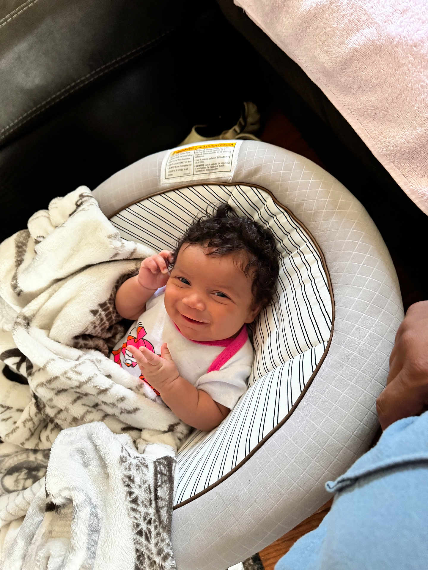 Aurora is registered to the contest to win money with this photo: baby, infant, blanket, baby_seat, smile, curly_hair, indoor, cozy, comfort, child, cute, person, clothing, soft_texture, pattern, relaxing, happy, portrait, toddler, hands