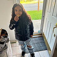 Aliyah joined the competition — help win amazing prizes! autumn, black_shoes, casual_clothing, child, curly_hair, door, doormat, grass, indoor, long_hair, outdoor_view, person, puffer_vest, ripped_jeans, shoe_rack, snack, tiled_floor, trees, waffle, window