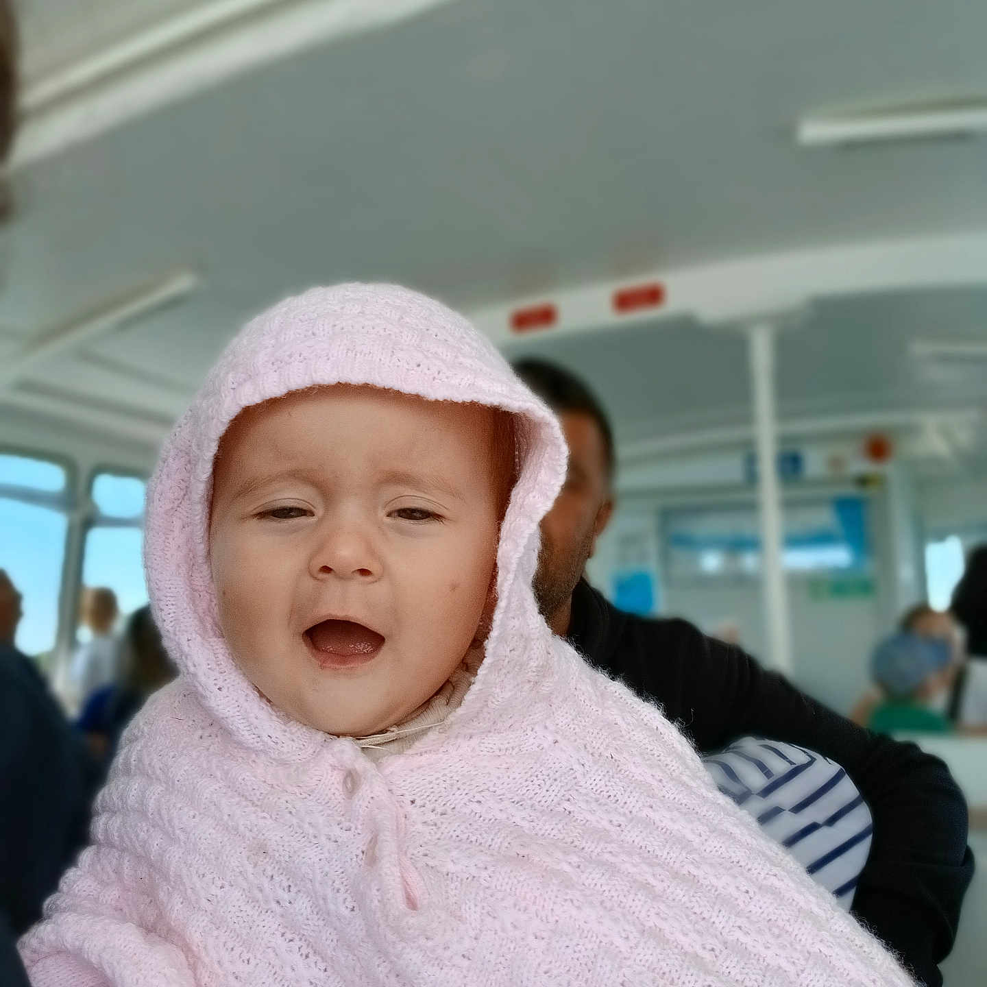 Pauline participe au concours pour gagner de l'argent avec cette photo : baby, blurred_background, bus_interior, candid, child, cozy, expression, face, happy, indoor, knitted_blanket, people, person, pink_hood, portrait, public_transport, seated, transportation, travel, warm_clothing