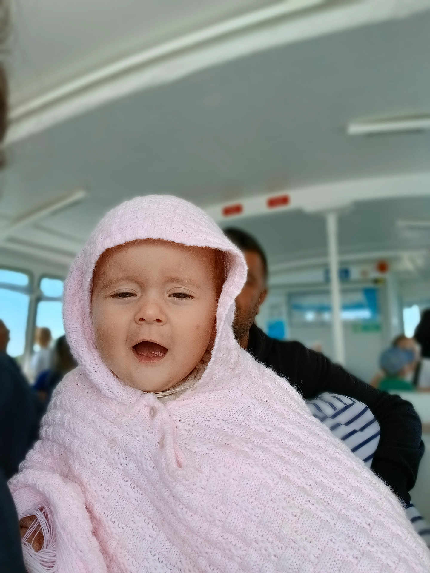 Pauline participe au concours pour gagner de l'argent avec cette photo : baby, child, pink_hood, knitted_blanket, portrait, indoor, people, transportation, bus_interior, seated, face, expression, cozy, warm_clothing, candid, person, happy, travel, public_transport, blurred_background