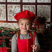 Kaycee joined the competition — help win amazing prizes! child, smiling, chef_hat, red_apron, wooden_bowl, whisk, spoon, kitchen, christmas_decorations, holiday, snowy_window, baking, flour_bag, festive, gingerbread_card, wooden_table, pigtails, sweater, indoors, happy