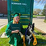 Chance is registered to the contest to win money with this photo: black_and_white_dog, blue_sky, cap_and_gown, daytime, diploma, dog, glasses, graduate, grass, leash, medal, outdoor, person, sidewalk, sign, smiling_person, stethoscope, tree, veterinary_technology, yellow_sash