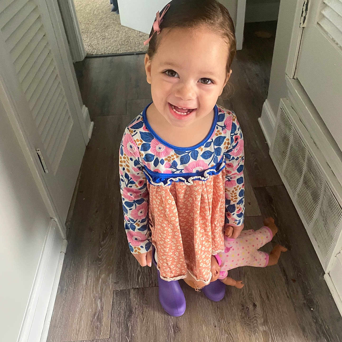 Keeloah joined the competition — help win amazing prizes! boots, child, cute, doll, dress, flooring, hairclip, hallway, happy, indoor, long_sleeves, patterned_clothing, person, smiling, standing, toddler, toy, white_walls, wood_floor, young_child