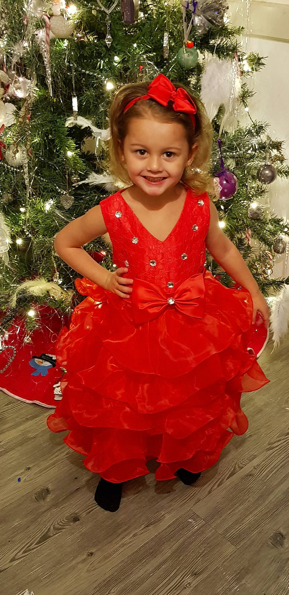 D'Joulya participe au concours pour gagner de l'argent avec cette photo : child, child_model, christmas, christmas_decoration, christmas_eve, christmas_tree, clothing, costume, dress, holiday, joy, person, red, ruffle, smile, toddler
