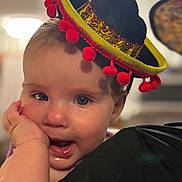 Stella joined the competition — help win amazing prizes! baby, child, face, hat, sombrero, hand, expression, cute, portrait, headwear, infant, closeup, smile, indoor, person, clothing, cheek, curious, joyful, soft_background