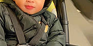 Elliot is registered to the contest to win money with this photo: baby, bodypart, car, car_interior, clothing, coat, face, finger, hand, happy, head, hood, jacket, person, photography, portrait, smile, stroller, transportation, vehicle