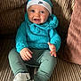 baby, smiling, blue_hat, knitted_sweater, sitting, couch, white_shoes, happy, child, infant, cute, portrait, cozy, indoor, clothing, hands, feet, face, young_child, nike