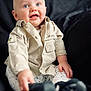 baby, child, infant, blue_eyes, shirt, pants, sitting, hand, face, smile, expression, indoor, clothing, footwear, portrait, young_child, cute, looking_up, person, background