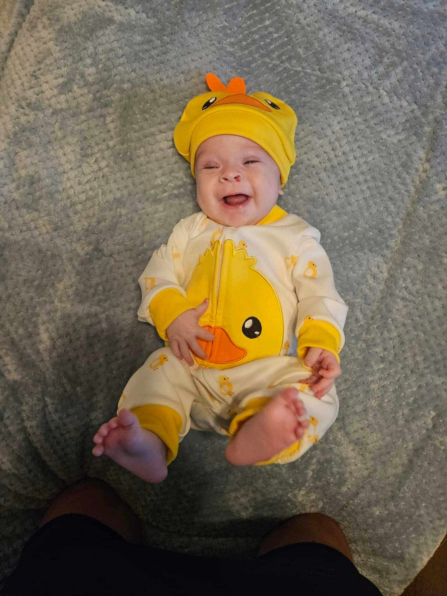 Daniel is registered to the contest to win money with this photo: baby, infant, smiling, yellow_hat, duck_outfit, cute, happy, lying_down, blanket, soft_texture, feet, child, one_person, indoors, playful, adorable, clothing, headwear, expression, portrait