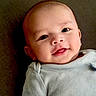 baby, casual_clothing, child, close_up, couch, eyes, face, gray_shirt, happy, head, home, indoor, infant, lying_down, mouth, photography, portrait, sitting, smiling, soft_lighting