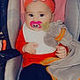 baby, black_pants, blanket, car_seat, child, clothing, cute, elephant, headband, holding, indoor, infant, pacifier, person, pink_pacifier, red_clothing, seat, soft_toy, stuffed_animal, toy