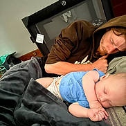 Declan joined the competition — help win amazing prizes! baby, adult_male, sleeping, blanket, blue_shirt, hoodie, bed, indoor, nap, cozy, playpen, resting, person, casual_clothing, hand, face, peaceful, home, toddler, relaxation