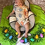 baby, infant, pacifier, sleeping, baby_seat, easter, easter_eggs, green_shredded_paper, bib, text_on_bib, bed, blanket, clothing, footwear, indoors, holiday, cute, child, person, celebration
