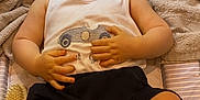 Robbie is registered to the contest to win money with this photo: baby, infant, smiling, happy, child, clothing, tank_top, shorts, legs, feet, hands, blanket, cushion, striped, indoor, floor, pacifier, brush, person, portrait