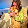 Larry is registered to the contest to win money with this photo: person, cat, orange_cat, fluffy_cat, hugging, indoor, cozy, sweater, couch, pillow, table, can, home, comfort, feline, pet, love, warmth, relaxation, casual