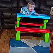 Branson joined the competition — help win amazing prizes! toddler, child, indoor, colorful_furniture, table, bench, carpet, rug, wood_floor, leather_couch, smiling, blonde_hair, playful, person, furniture, happy, crawling, wood, living_room, casual_clothing