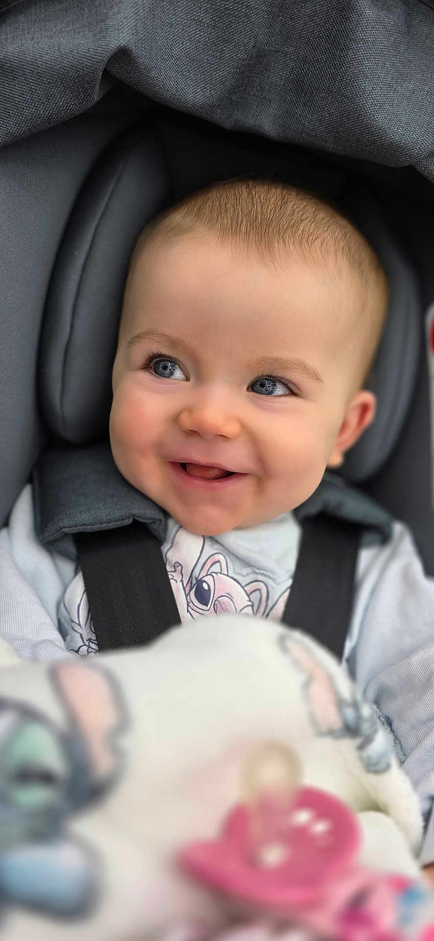 Ayla is registered to the contest to win money with this photo: baby, child, car_seat, smile, face, blue_eyes, blanket, pacifier, clothing, infant, seatbelt, cute, happy, portrait, indoors, soft_toys, head_support, baby_girl, warm, cozy