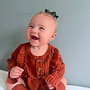 Amayah is registered to the contest to win money with this photo: baby, child, smiling, happy, sitting, knitwear, bow, cute, portrait, indoors, cozy, rust_color, socks, person, infant, closeup, headwear, buttoned, fashion, warm
