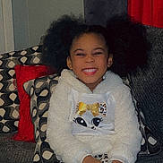 Leah is registered to the contest to win money with this photo: child, smiling, happy, pigtails, couch, pillows, red_curtain, white_hoodie, leopard_print, patterned_pillows, indoor, cozy, seated, cross_legged, young_child, cute, fashion, portrait, home, casual