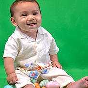 Josiah is registered to the contest to win money with this photo: baby, child, smiling, sitting, green_background, easter_eggs, toy_carrots, white_shirt, floral_pants, barefoot, cute, portrait, studio_photo, infant, happy, colorful, playful, indoors, one_person, toddler