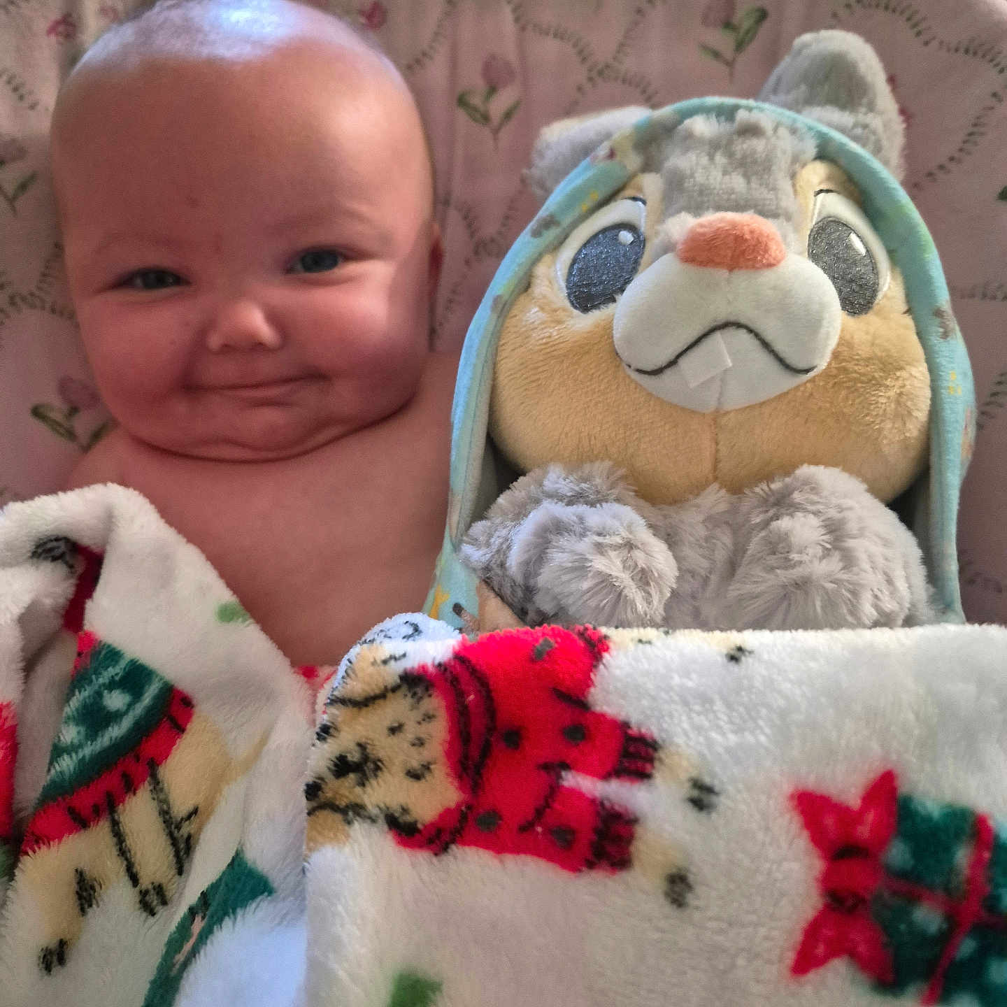 Emma is registered to the contest to win money with this photo: baby, blanket, plush_toy, bunny, hoodie, face, smile, child, cute, indoors, cozy, soft_toy, colorful, wrapped, toddler, portrait, happy, comfort, cuddly, resting