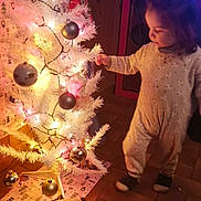 Diana Pille participe au concours pour gagner de l'argent avec cette photo : celebration, child, christmas, christmas_tree, cozy, curiosity, decorations, festive, floor, holiday, home, indoor, lights, ornaments, pajamas, person, toddler, toy, warm_lighting, wooden_paneling