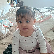 Aminah joined the competition — help win amazing prizes! baby, toddler, child, girl, pigtails, bangs, onesie, long_sleeve, sitting, bed, blanket, hairbrush, wipes, nightstand, window, portrait, indoors, cute, soft_lighting, smile