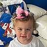 toddler, child, hat, pink, feather, white_shirt, blue_eyes, curly_hair, quilt, snowman, couch, indoor, portrait, smile, cute, rosy_cheeks, cozy, holiday, decor, furniture