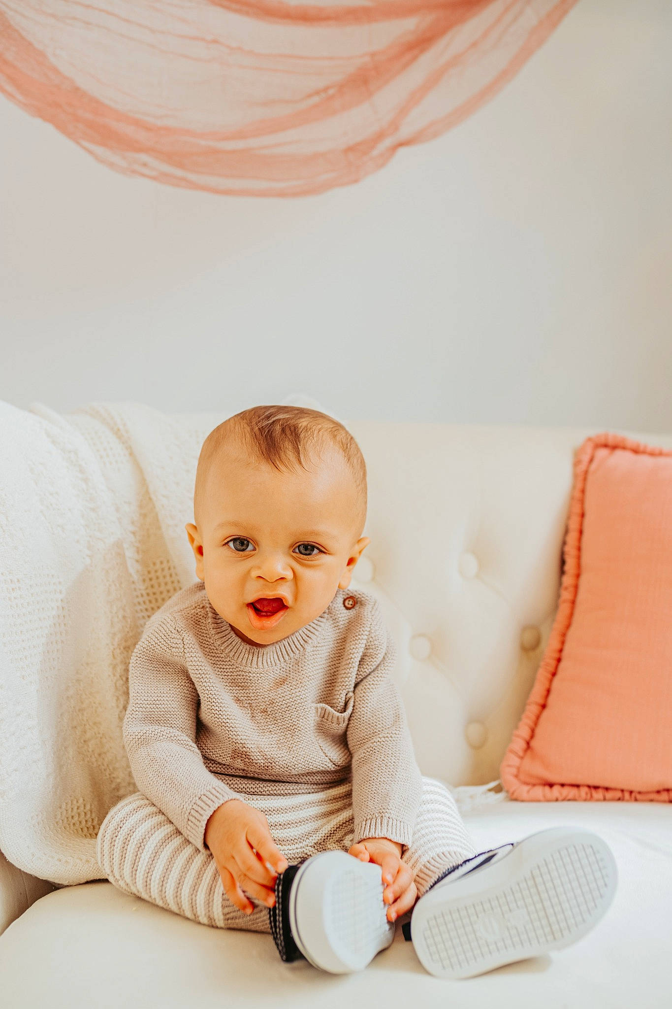 Zayne joined the competition — help win amazing prizes! baby, baby_toddler_clothing, child, comfort, couch, curtain, flooring, foot, happy, human_leg, knee, linens, orange, person, room, sitting, skin, sleeve, smile, textile