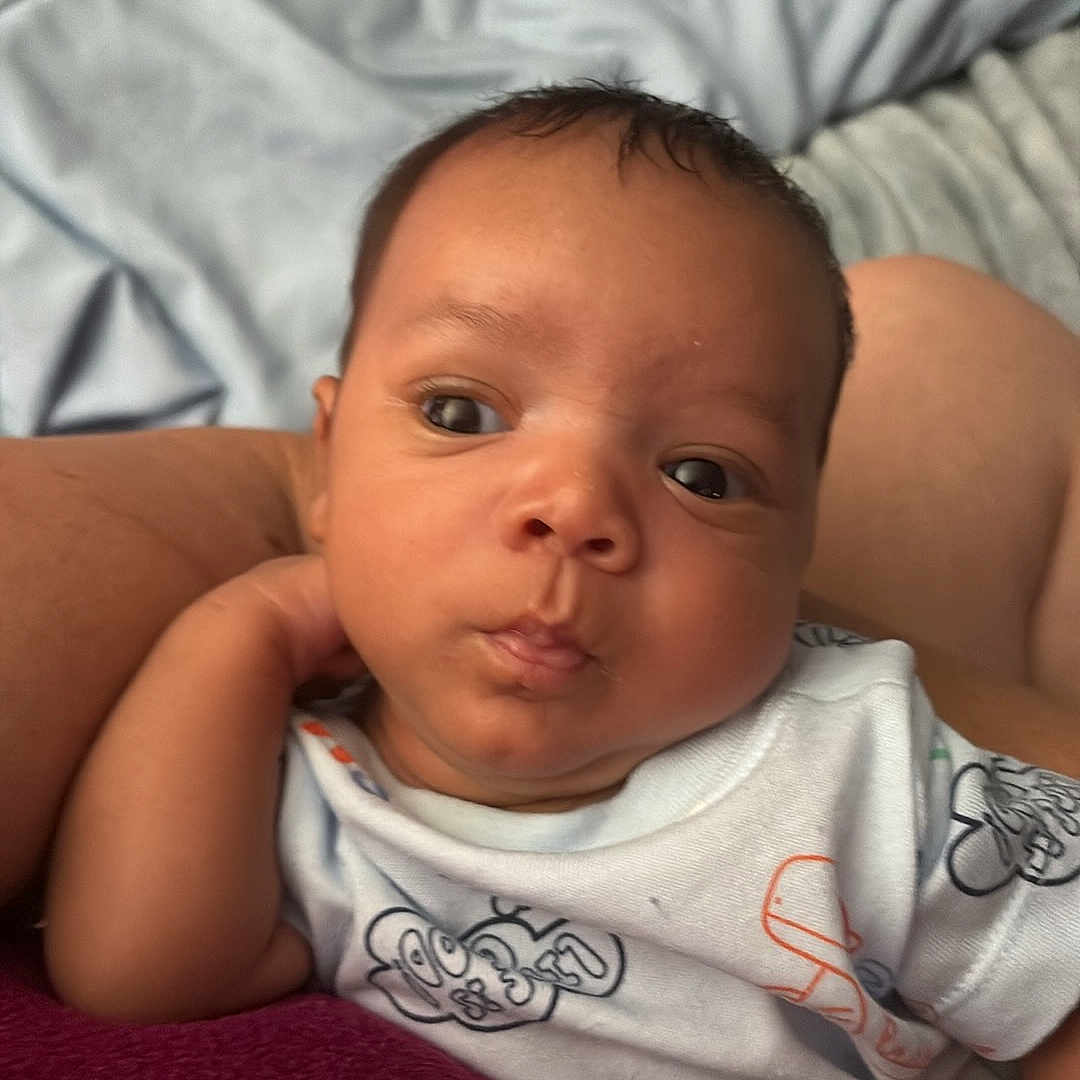 Tyler is registered to the contest to win money with this photo: arm, baby, bed, blanket, child, clothing, comfort, cute, expression, face, hand, indoor, infant, onesie, person, portrait, resting, skin, soft, young