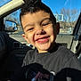 child, boy, smiling, teeth, car_interior, vehicle_window, sunlight, shadow, t_shirt, short_hair, happy, portrait, close_up, ear, cheek, dashboard, passenger_seat, basketball_hoop, outdoor_background, seat