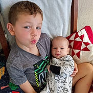 Archer joined the competition — help win amazing prizes! child, baby, boy, infant, clothing, onesie, pillow, quilt, blanket, sitting, indoor, portrait, cute, face, expression, holding, furniture, head, smile, family
