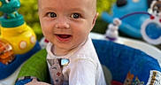 Dawson-Micheal joined the competition — help win amazing prizes! baby, child, infant, smiling, happy, portrait, face, outdoor, playground, activity_center, toys, colorful, seated, short_hair, white_shirt, blue_seat, green_grass, backyard, close_up, photography