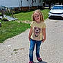 Alaya is registered to the contest to win money with this photo: child, girl, smiling, standing, tshirt, jeans, sandals, gravel, driveway, house, car, grass, sunny, outdoor, daytime, person, happy, blonde_hair, casual_clothing, residential