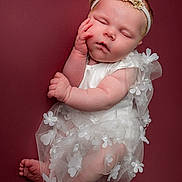 Harper is registered to the contest to win money with this photo: baby, sleeping, infant, white_dress, headband, flower, tulle, cute, peaceful, portrait, newborn, soft_skin, closed_eyes, hand_on_face, barefoot, studio, maroon_background, adorable, child, resting