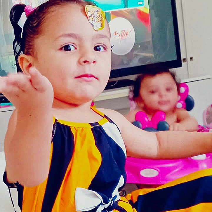 Myriam Sarah a rejoint le concours — aidez-le/la à gagner de superbes lots ! baby, black, child, cute, expression, family_photos, furniture, home, indoor, living_room, person, pink, playful, portrait, striped_clothing, television, toddler, walker, white, yellow