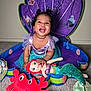 toddler, child, smiling, mermaid_costume, plush_toy, ariel_doll, red_crab_plush, play_mat, indoor, carpet, purple, green, blue, cute, happy, portrait, baby, costume, toy, fun