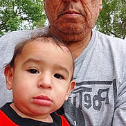 Dallas is registered to the contest to win money with this photo: child, toddler, man, glasses, outdoor, trees, shirt, gray_tshirt, red_shirt, portrait, people, family, face, casual_clothing, nature, adult, expression, holding, close_up, daylight