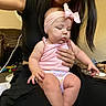 Wrenlee joined the competition — help win amazing prizes! baby, child, infant, person, pink_clothing, headband, bow, sitting, indoor, human_hand, long_hair, furniture, toy, living_room, carpet, couch, sleepy, cute, casual, home