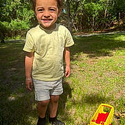 Randolph joined the competition — help win amazing prizes! child, smiling, outdoor, grass, trees, toy, yellow_toy, shorts, tshirt, sunlight, nature, happy, play, boy, forest, daylight, feet, shadow, casual_clothing, park