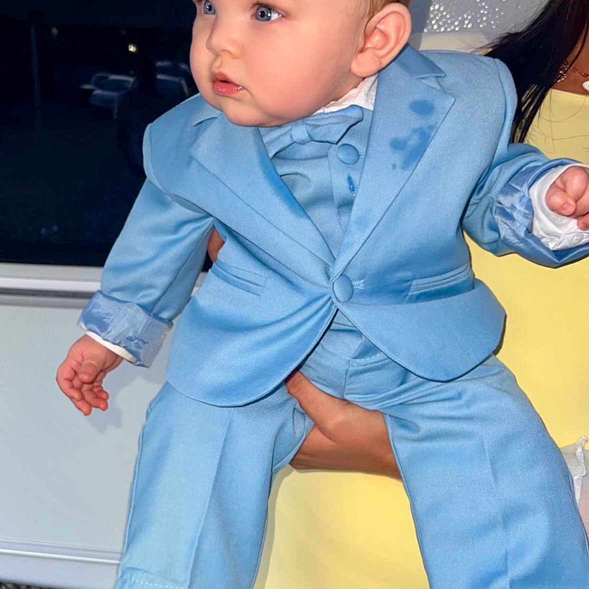 Ezra a rejoint le concours — aidez-le/la à gagner de superbes lots ! baby, child, blue_suit, bow_tie, formal_wear, person, portrait, indoor, hand, yellow_clothing, footwear, black_shoes, curly_hair, cute, small_hands, face, looking_away, holding, infant, young_child